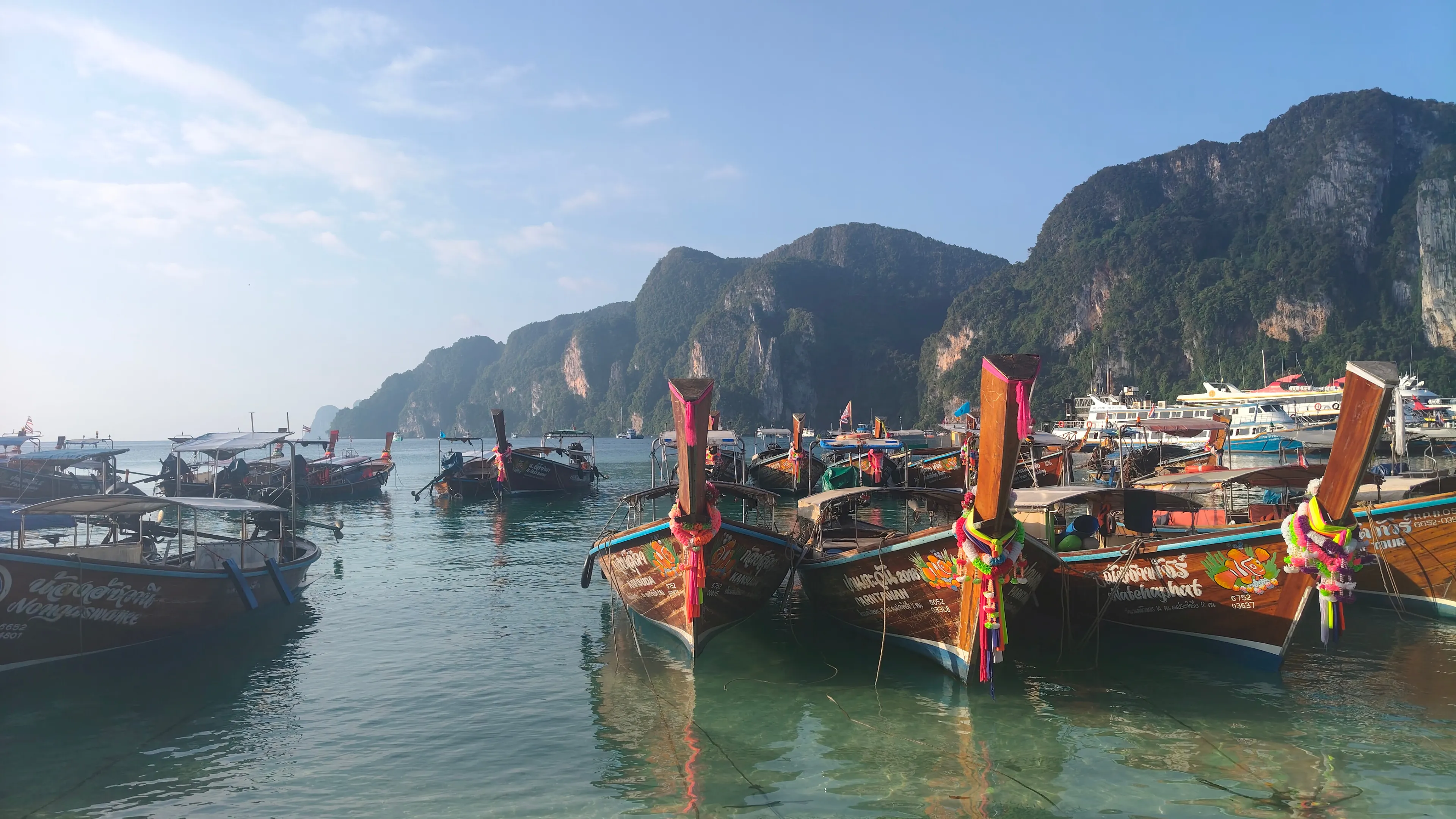 Traditional private longtail boat cruising beside the Phi Phi cliffs