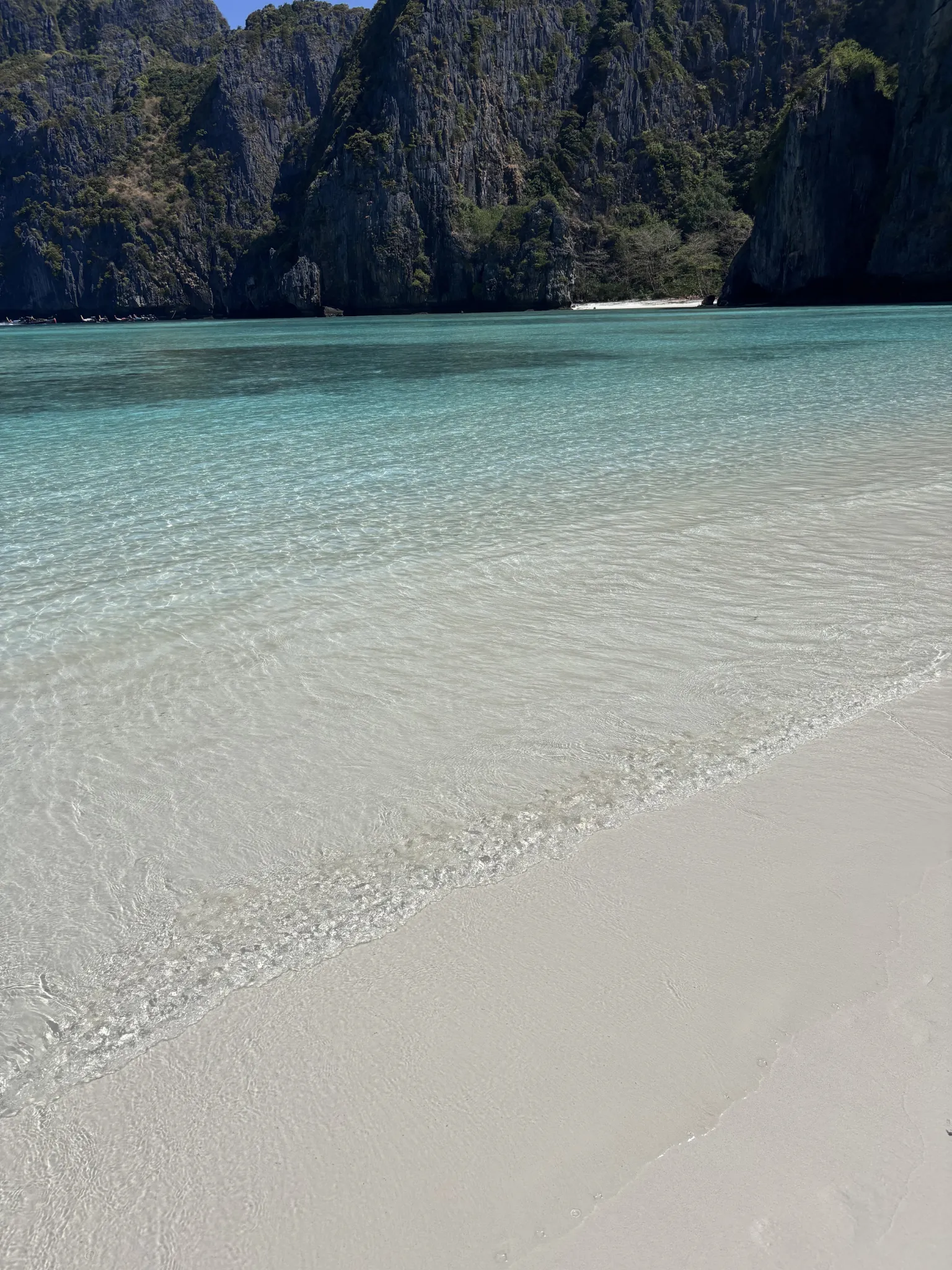Clear turquoise water and a quiet beach beneath Phi Phi cliffs