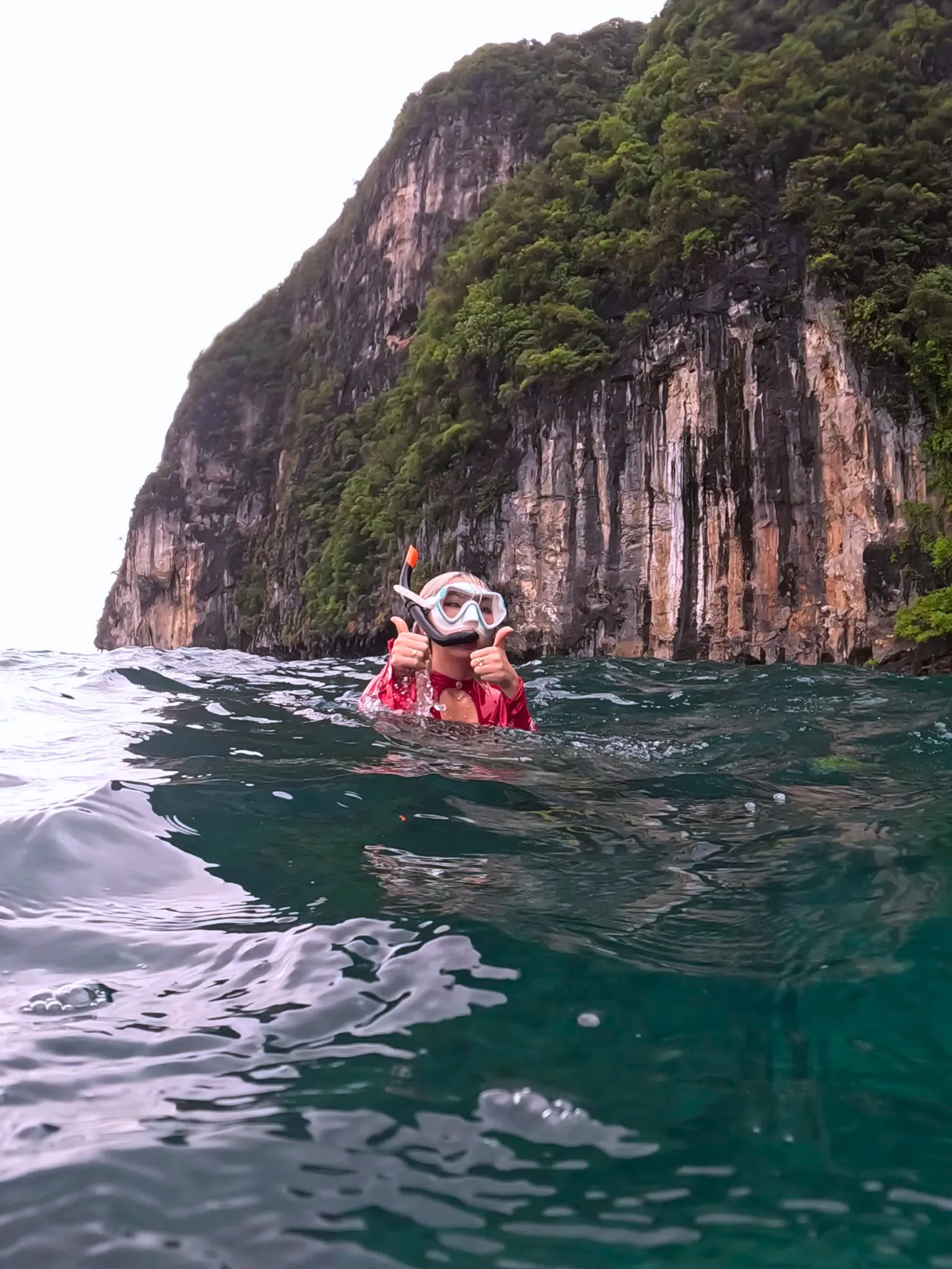 Woman snorkeling at the surface beneath Phi Phi cliffs