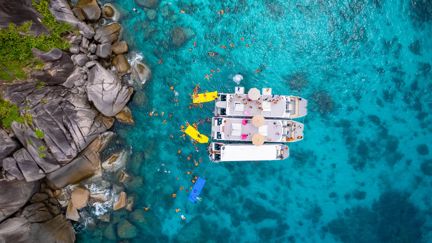 Aerial view of boats and snorkelers in the clear water of the Similan Islands